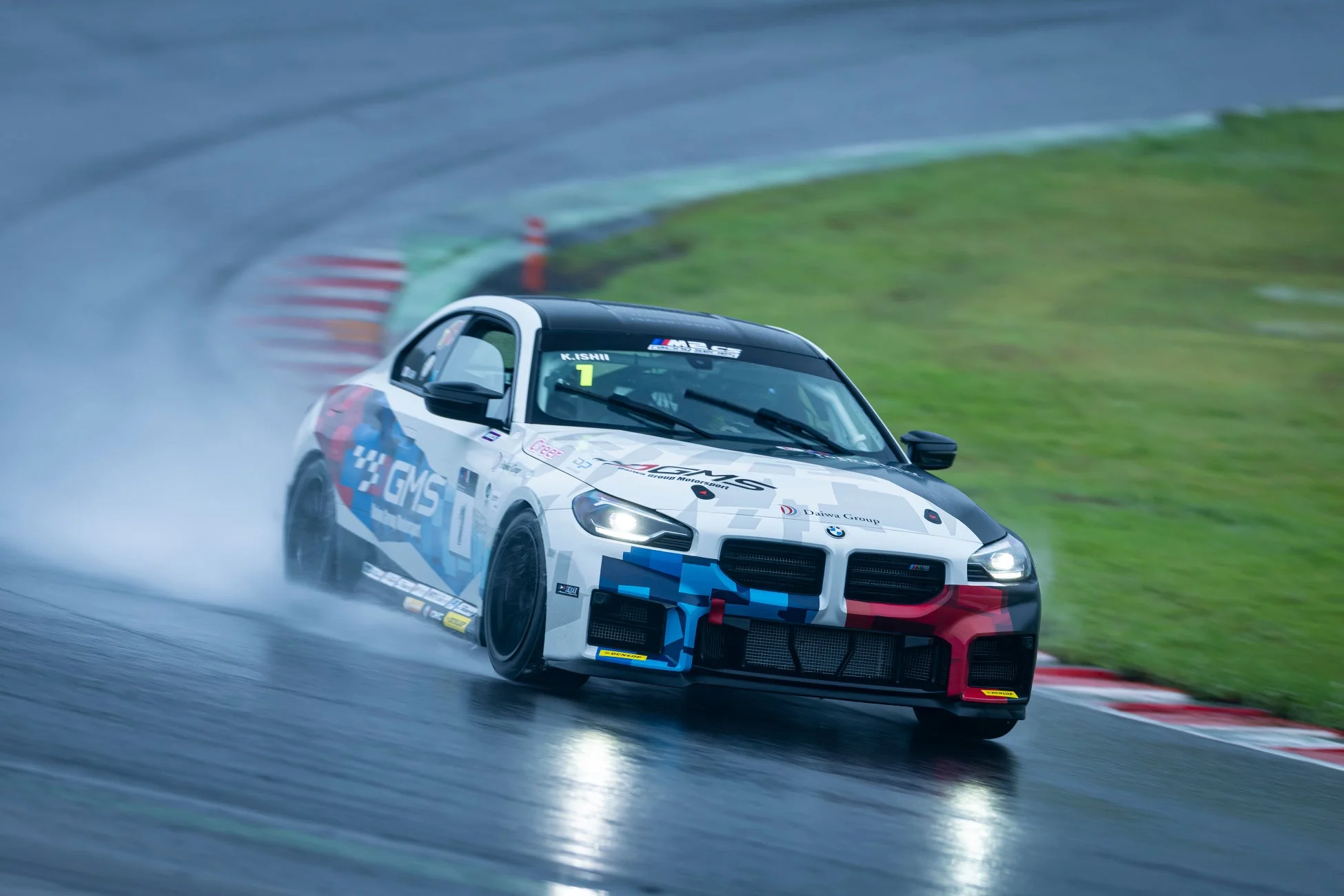 雨のサーキットを疾走する白いBMW Mシリーズのレースカー