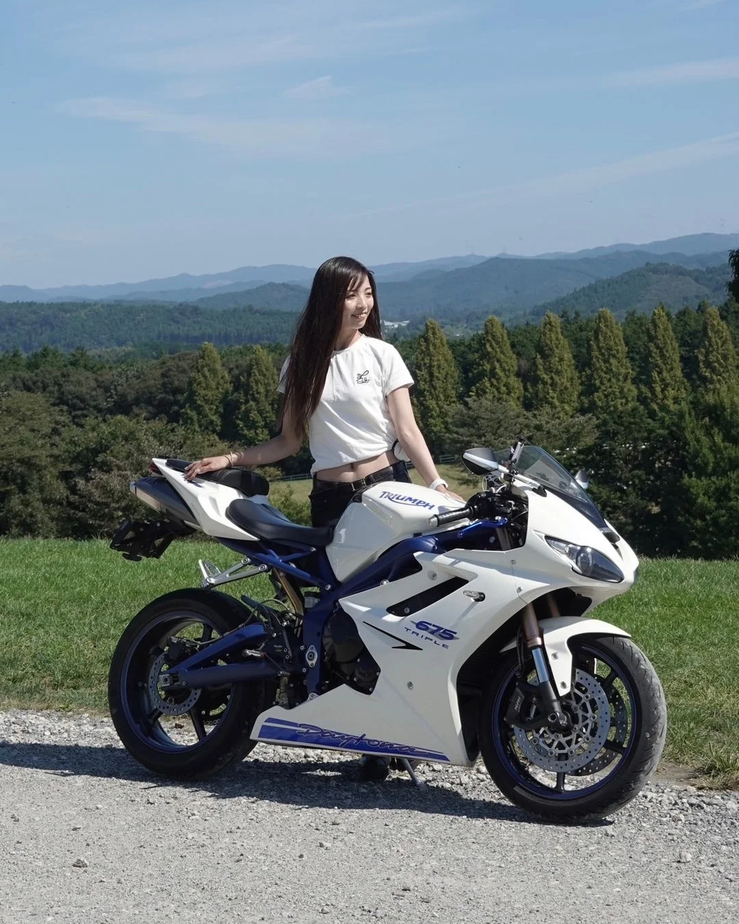 白いTriumph Daytona 675とポーズをとる女性