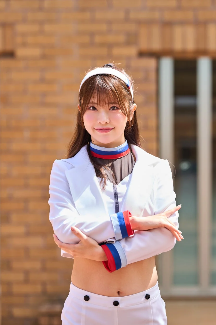 白いジャケットとパンツを着用した若い女性が屋外で笑顔を見せています